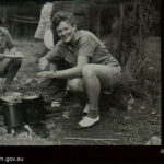 A WAAAF officer trainee prepares a meal over an open fire